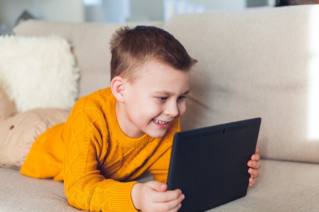 Foto chico lindo usa una tableta. el niño habla por enlace de video. cuarentena. hogar.