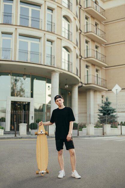 Chico con un longboard posa en la cámara Espacio de copia de fondo