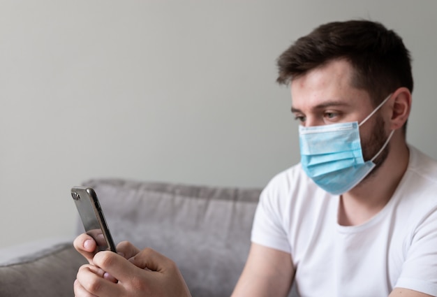 Foto chico en una máscara médica usando un teléfono