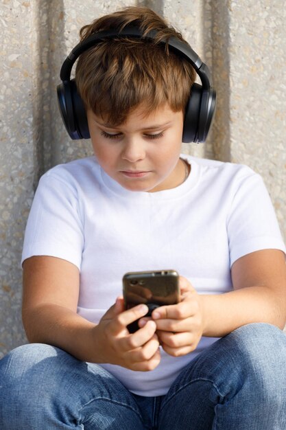 Chico de moda en auriculares con smartphone escuchando música en el parque