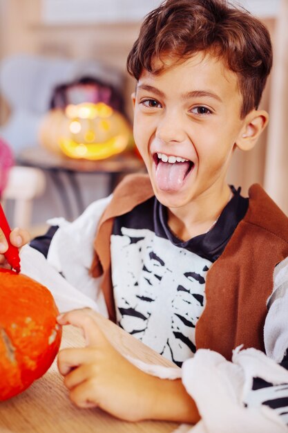 Chico mono. Lindo niño de ojos oscuros con disfraz de esqueleto para la fiesta familiar de Halloween para colorear calabaza