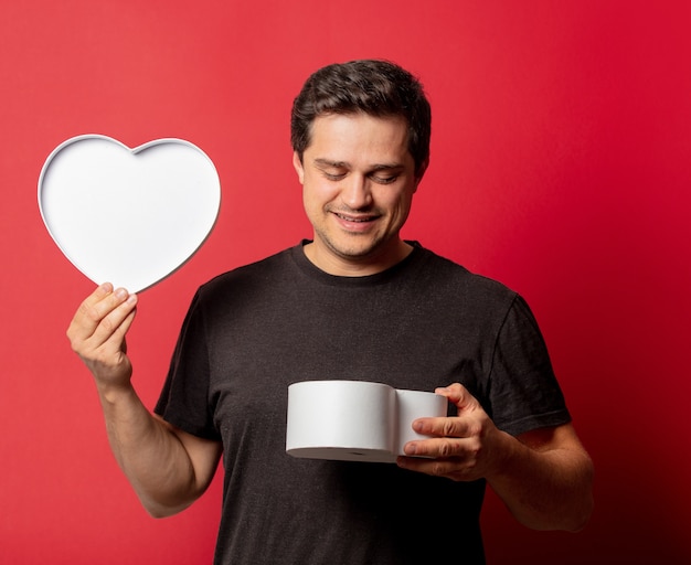 Chico morena con caja en forma de corazón en espacio rojo