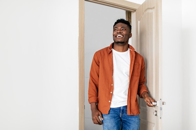 Chico negro alegre entrando en un nuevo hogar abriendo la puerta