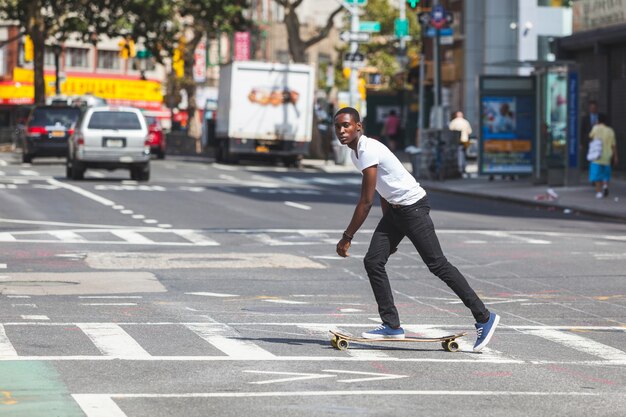 Chico negro patinando con longboard en la carretera