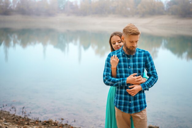 Un chico con una niña de pie en el lago en un abrazo.