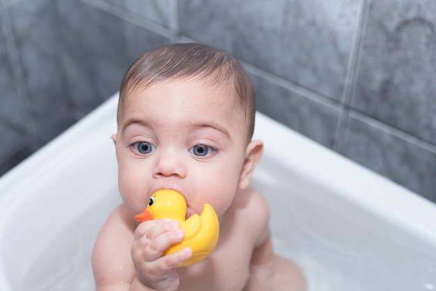 Chico de ojos azules bañándose en la bañera