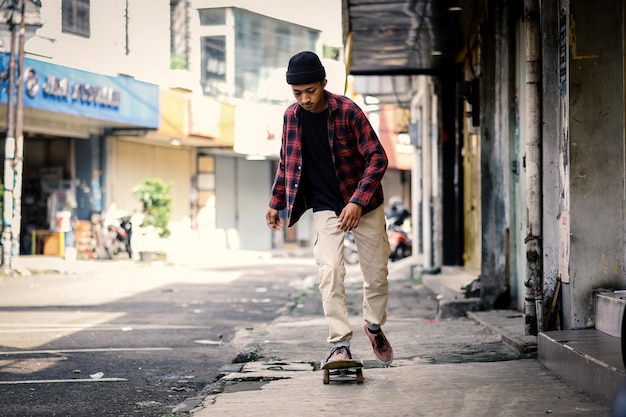 Chico patinador con estilo montando en patineta en la calle peatonal