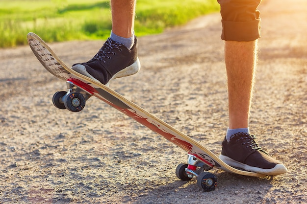 El chico se para en una patineta está en la carretera hermosa tonificación.