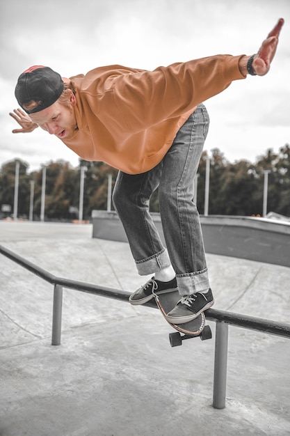 Chico en patineta volando sobre la barandilla en skatepark