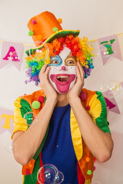 Chico payaso alegre de vacaciones entre pompas de jabón