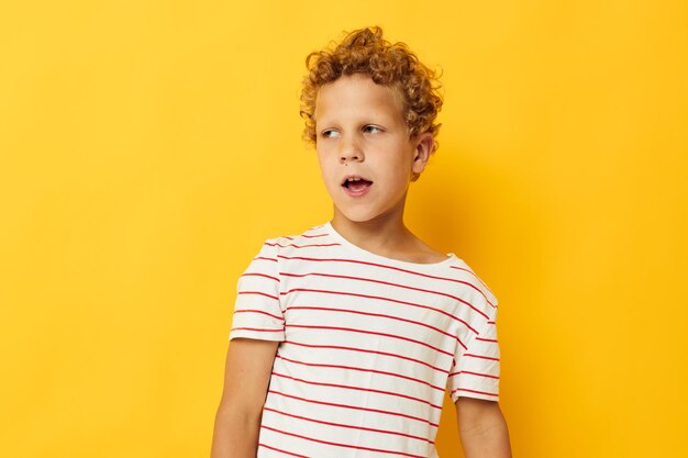 Chico con pelo rizado en una camiseta a rayas de fondo amarillo.