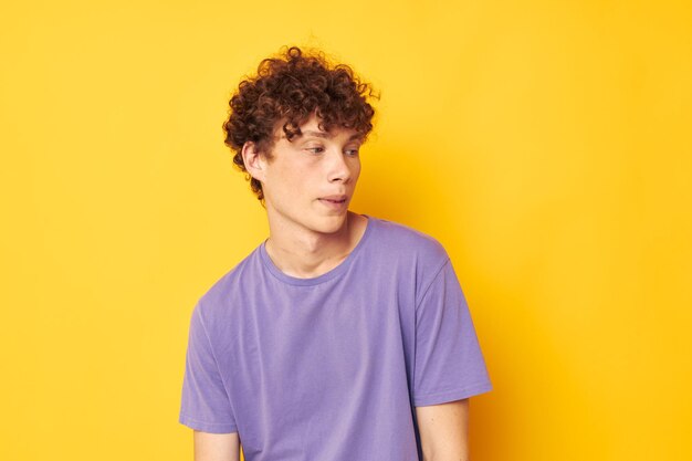 Chico con el pelo rizado en camisetas púrpura estudio fondo amarillo