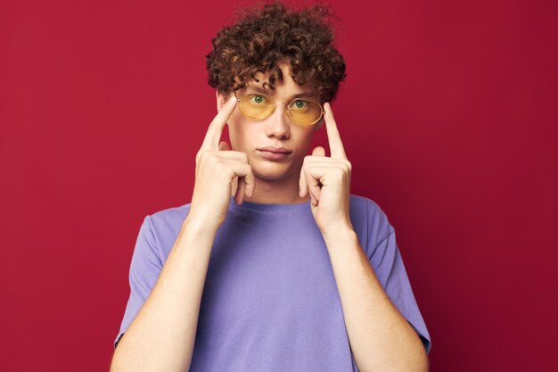 Chico con pelo rizado rojo en gafas amarillas camiseta morada emociones estilo juvenil