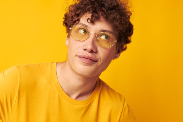 Chico con pelo rizado rojo con gafas elegantes camiseta amarilla posando Estilo de vida inalterado