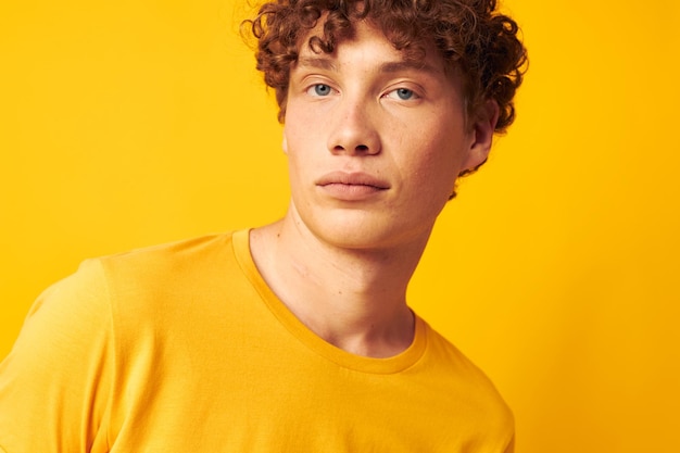 Chico con pelo rizado rojo gafas de estilo juvenil studio ropa casual fondo amarillo inalterado