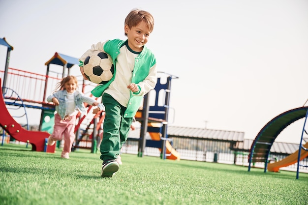 Foto el chico está con la pelota de fútbol los niños se están divirtiendo en el patio de recreo