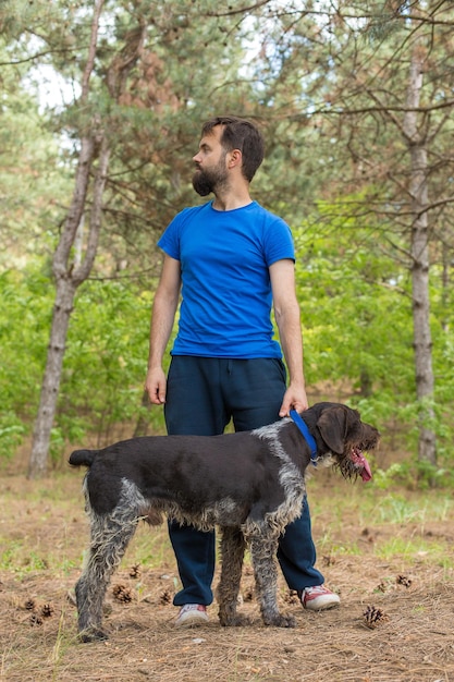 El chico con el perro en el parque, perro guardián de caza alemán drahthaar