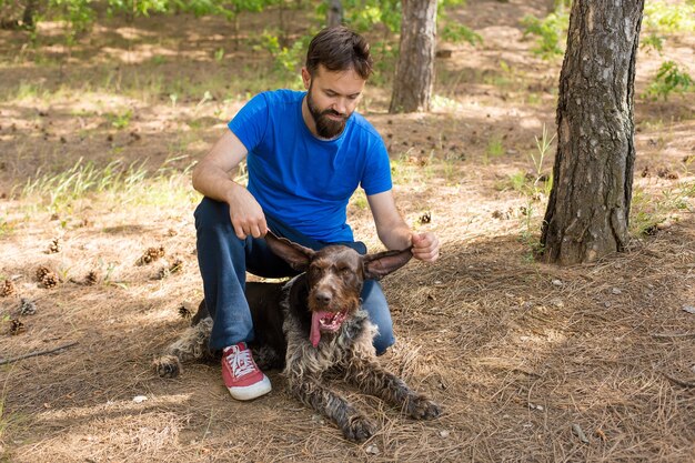 El chico con el perro en el parque perro guardián de caza alemán drahthaar