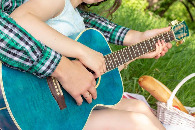 Chico de picnic de verano le enseña a la chica a tocar la guitarra, el amor, la ternura cálida