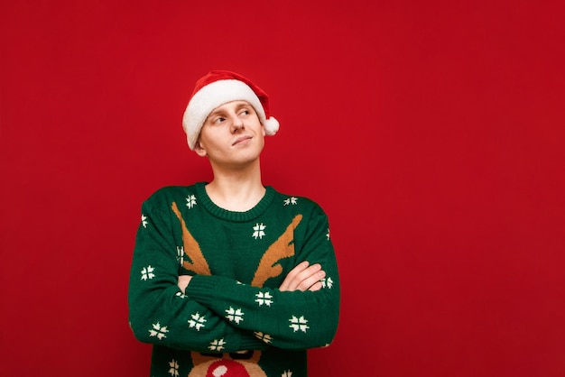 Chico positivo en ropa de Navidad aislado sobre fondo rojo.