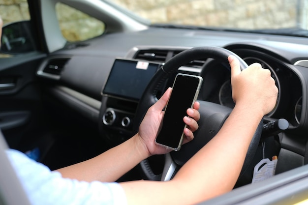 Un chico que usa el teléfono móvil mientras conduce el coche.