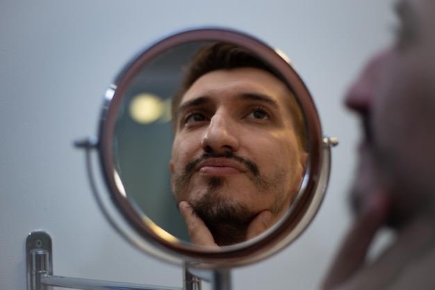 El chico de la rara barba se mira en el espejo del baño de una manera conmovida