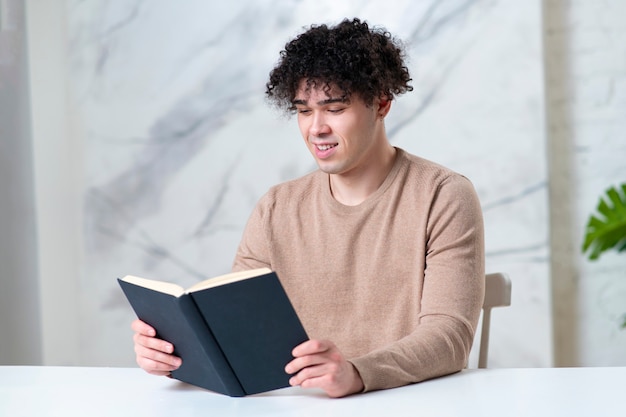 Chico de retrato sosteniendo un libro sobre fondo de mármol blanco