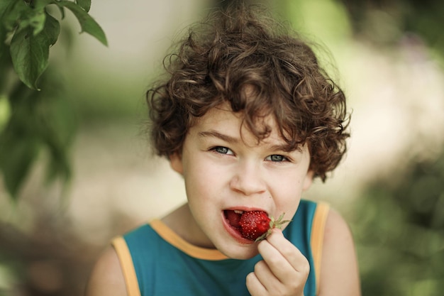 Chico rizado comiendo fresas maduras