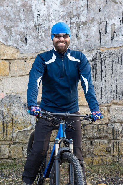 Un chico en ropa deportiva montando ropa en una bicicleta de montaña en un muro de hormigón de ladrillo vintage