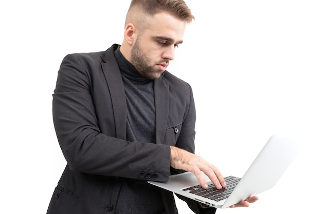 Un chico en ropa de negocios está trabajando en una computadora portátil sobre un fondo blanco.