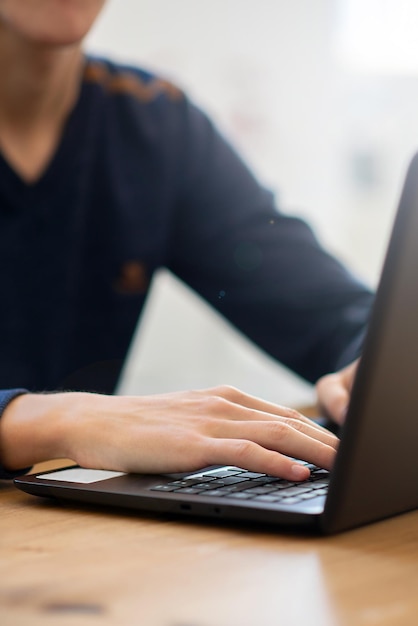 Un chico sin rostro trabaja en una cafetería para una laptop