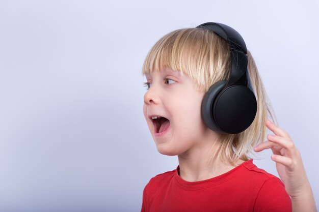 Chico rubio con auriculares escuchando música y cantando