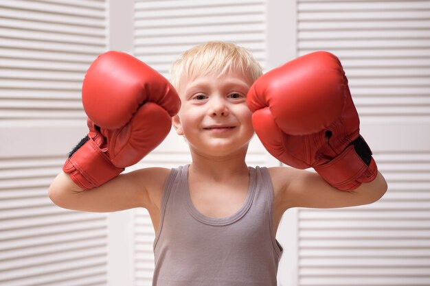 Chico rubio encantador en guantes de boxeo rojos. Deportes