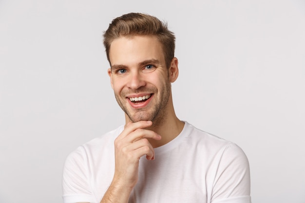 Chico rubio guapo con ojos azules y camiseta blanca sonriendo