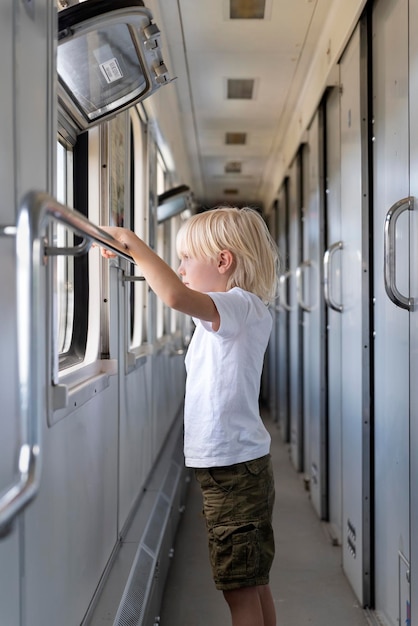 Chico rubio con interés mira por la ventana del tren Viajar con niños