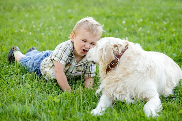 Chico rubio lindo niño con golden retriever al aire libre