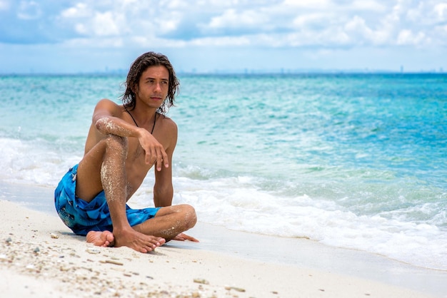 El chico sentado en la playa