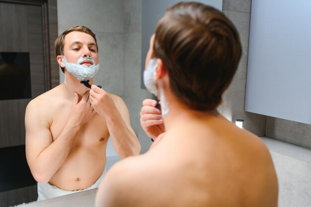 Foto chico serio afeitándose la barba