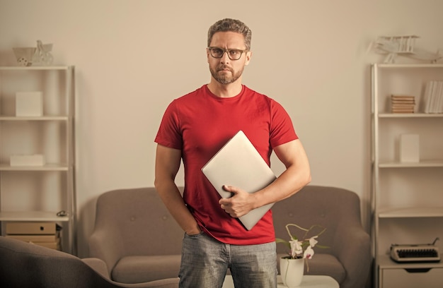 Chico serio en camiseta roja y gafas tiene pc freelancer