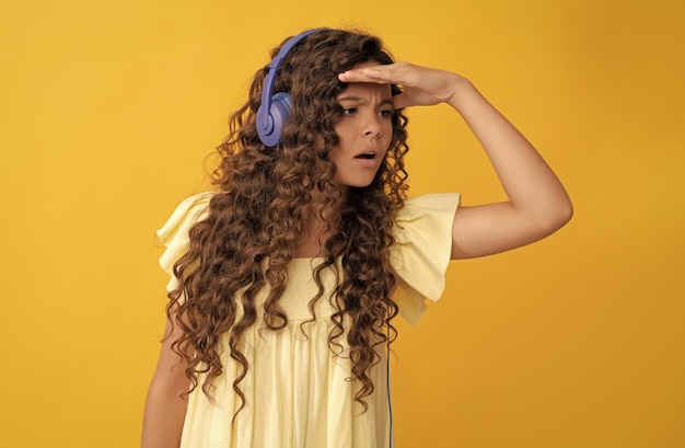 Chico serio escucha música en auriculares inalámbricos mirando hacia otro lado de vuelta a la escuela