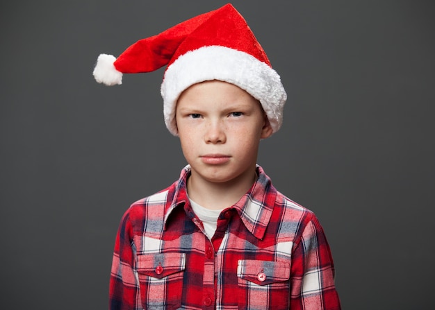 Chico serio en gorro rojo de Navidad