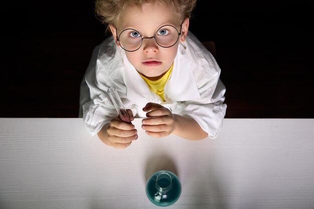 Chico serio en uniforme y gafas realiza experimentos químicos en laboratorio