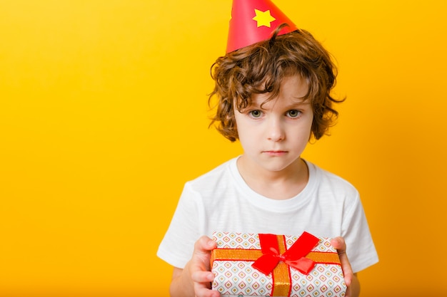 Chico solitario en gorro de fiesta con regalo.