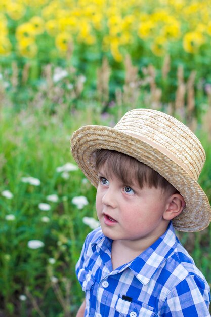 Chico en un sombrero en un campo de girasoles