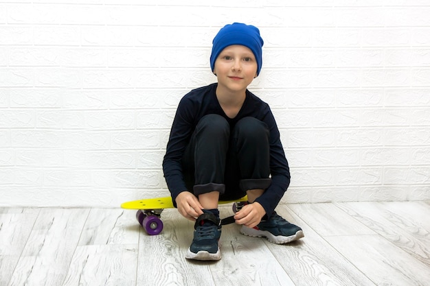 Un chico con sombrero se sube las zapatillas mientras se sienta en una patineta con luz de neón