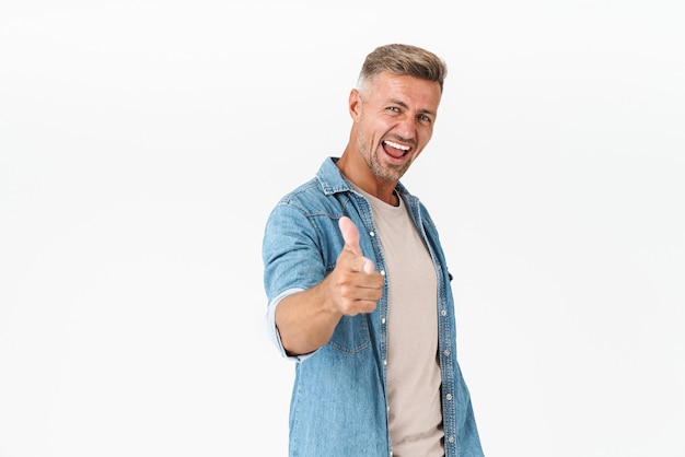 Chico sonriente en camisa de mezclilla regocijándose y gesticulando con el dedo índice aislado en blanco