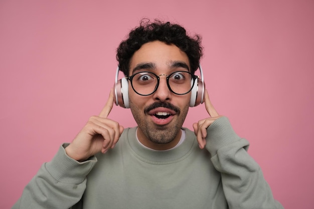 chico sorprendido y emocionado con auriculares y dedos apuntando a las orejas