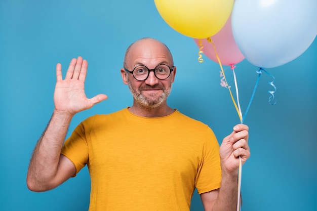 Chico sosteniendo globos sonriendo dando la bienvenida a sus amigos