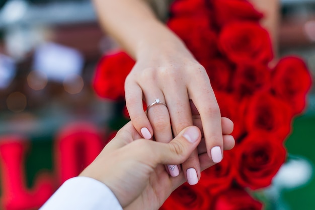 El chico sostiene la mano de la niña en su dedo anular, un anillo dorado