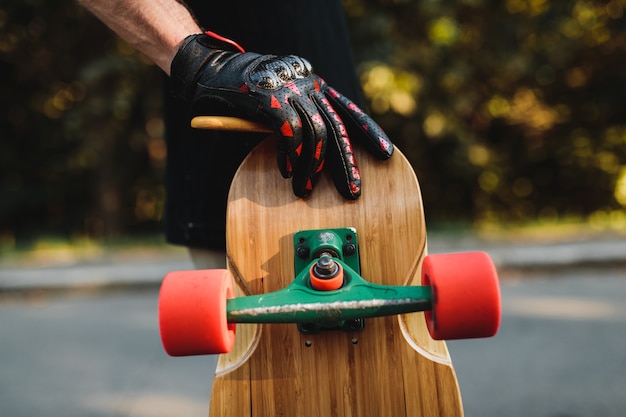 El chico sostiene una tabla con ruedas rojas. Skate en la ciudad eterna. Foto de alta calidad